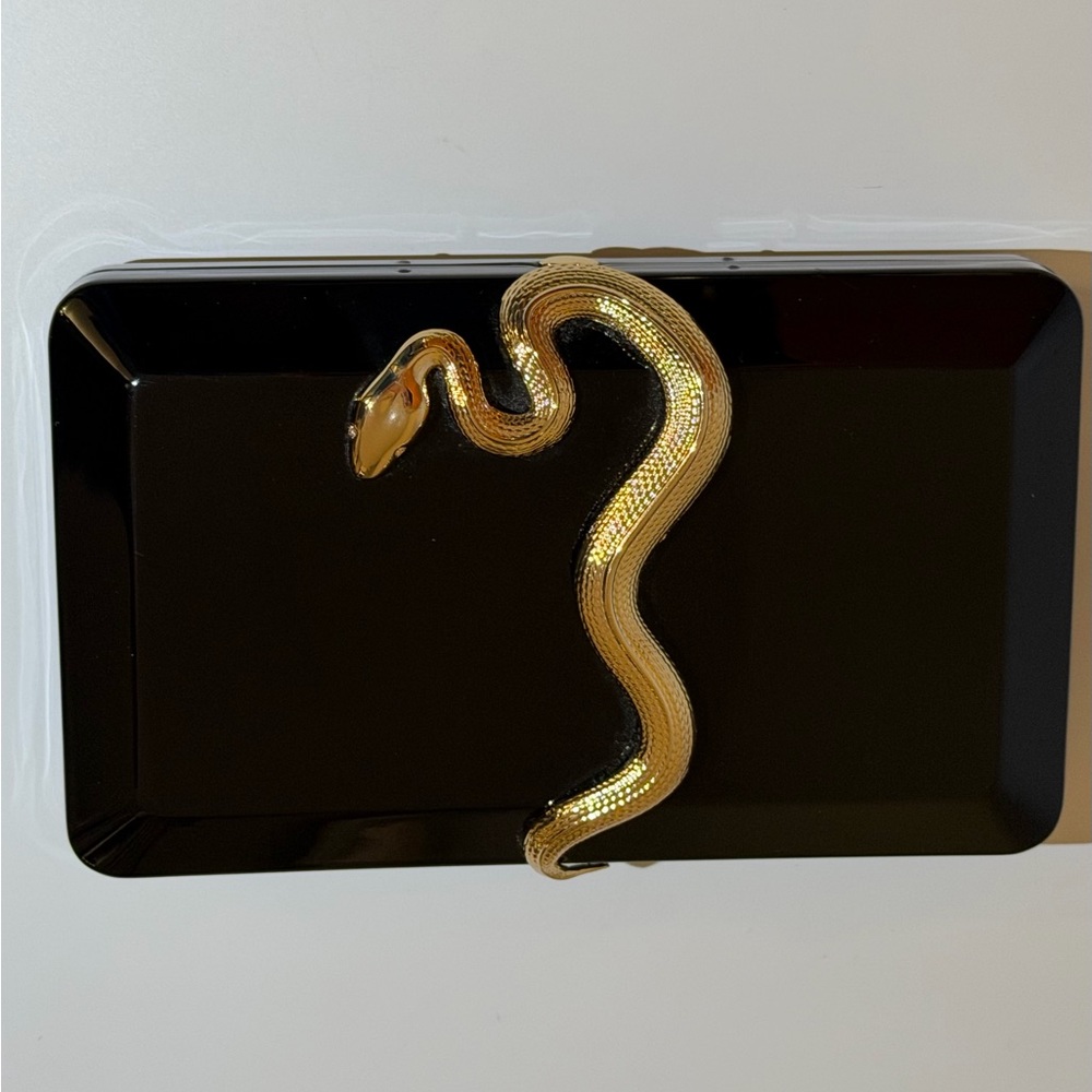Kilian black enamel clutch featuring a gold-toned snake, a signature accessory.